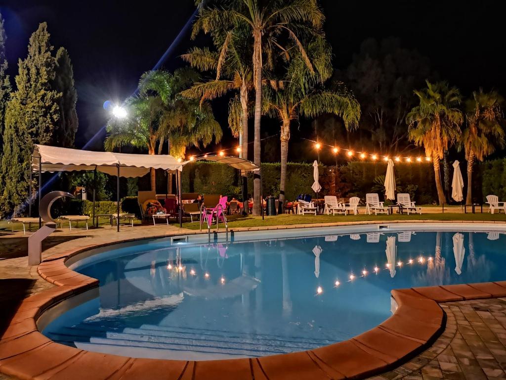 una piscina por la noche con mesas y sillas en Hotel ausonia en Corigliano Calabro