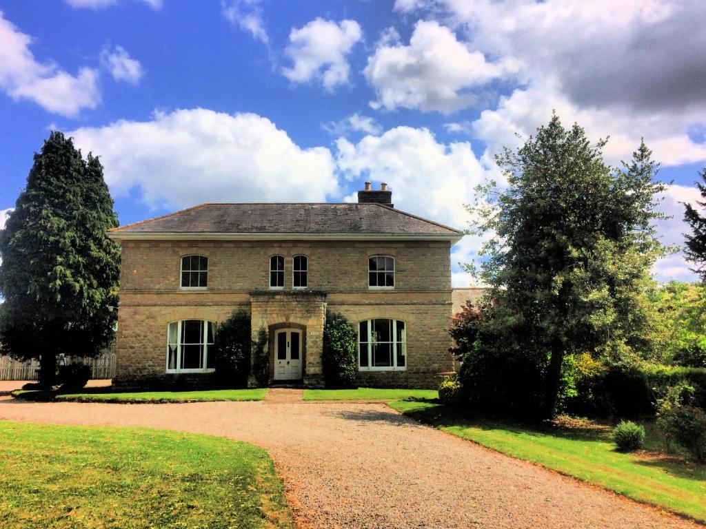 an old stone house with a driveway in front at Walltree House in Brackley