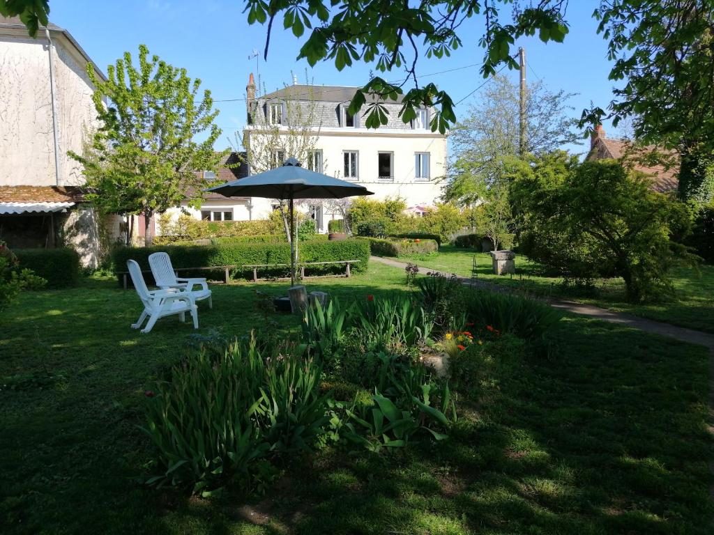 a yard with a white chair and an umbrella at une maison à la campagne in Beaune-la-Rolande