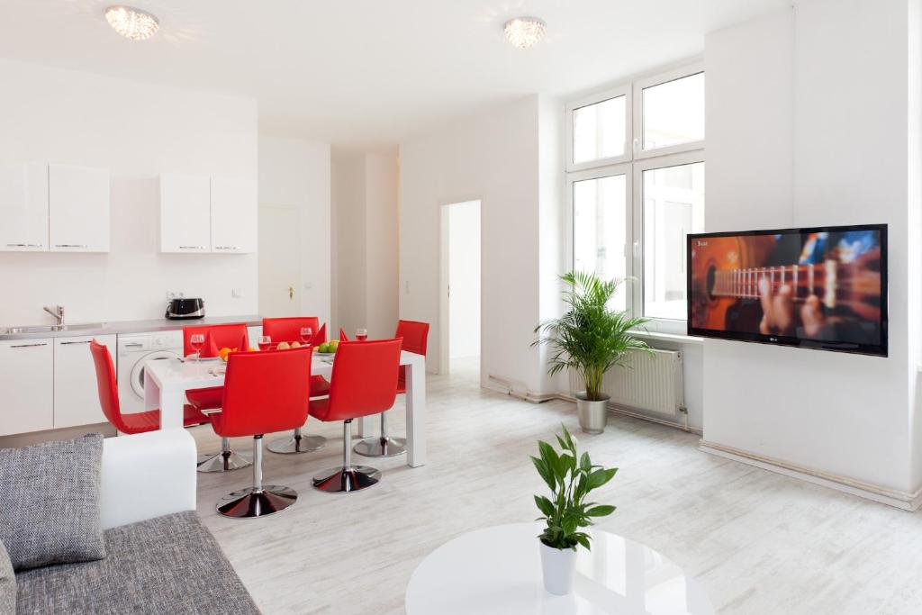 a white living room with a table and red chairs at The Cloud in Berlin