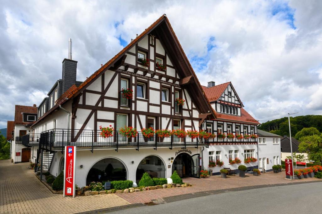 un gran edificio blanco con cajas de flores en el balcón en Hotel Antoniushütte, en Balve