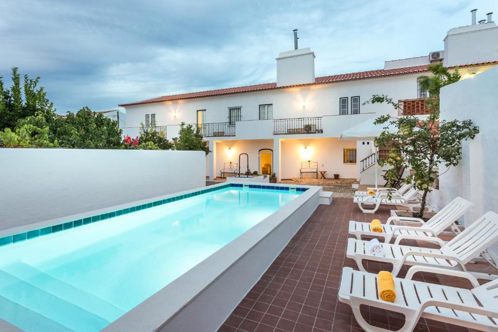 a villa with a swimming pool and lounge chairs at Hospedaria da Roda in Sousel