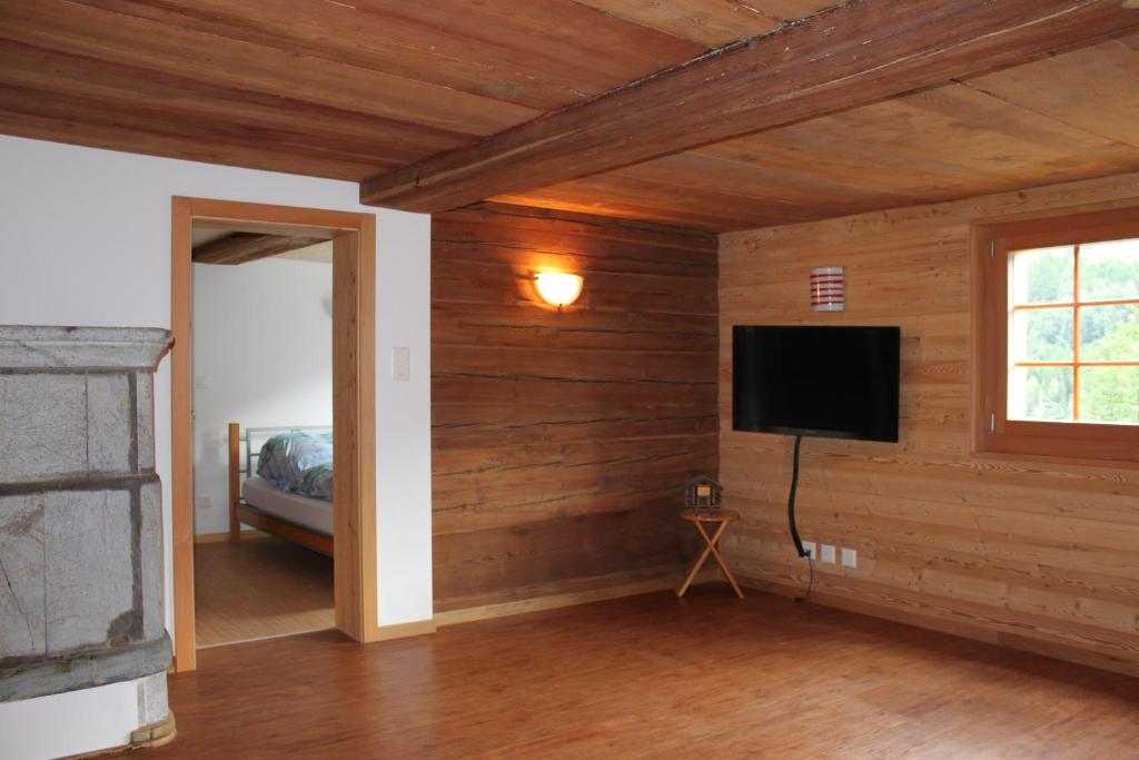 a room with wooden walls with a television and a bed at Jentsch Haus in Niederwald