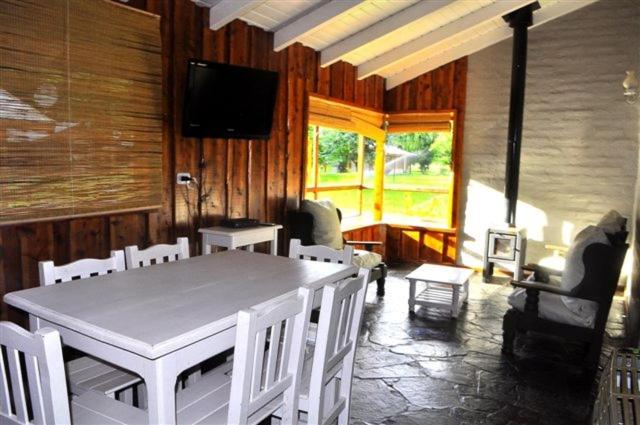 a dining room with a table and chairs and a television at Cabañas y Hosteria Aldea Los Huemules in El Hoyo