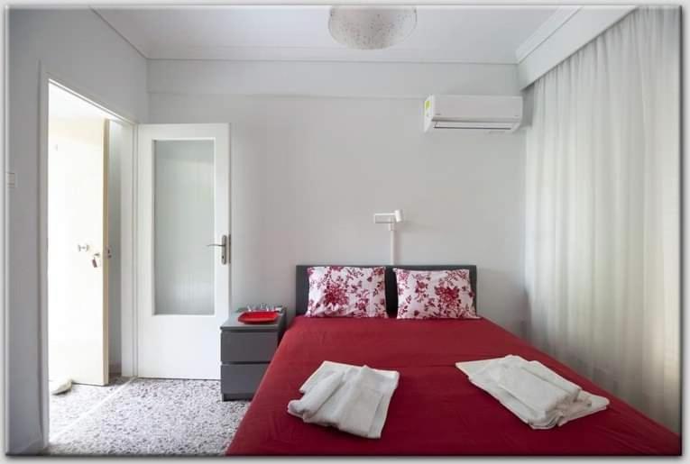 a bedroom with a red bed with two pillows at Anni's cozy apartments 50m from the beach in Agia Triada