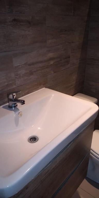 a white sink in a bathroom with a toilet at Inaki Uhi Hotel in Hanga Roa