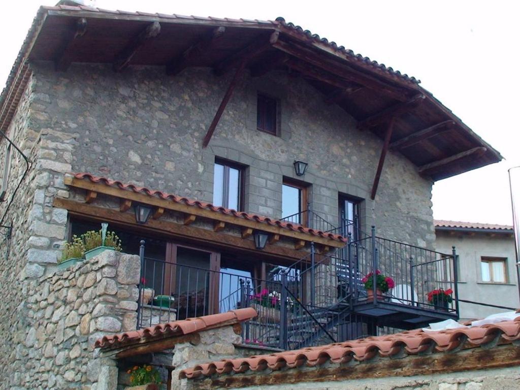 ein Steingebäude mit einem Balkon mit Blumen darauf in der Unterkunft Cal Sandic in Aransá