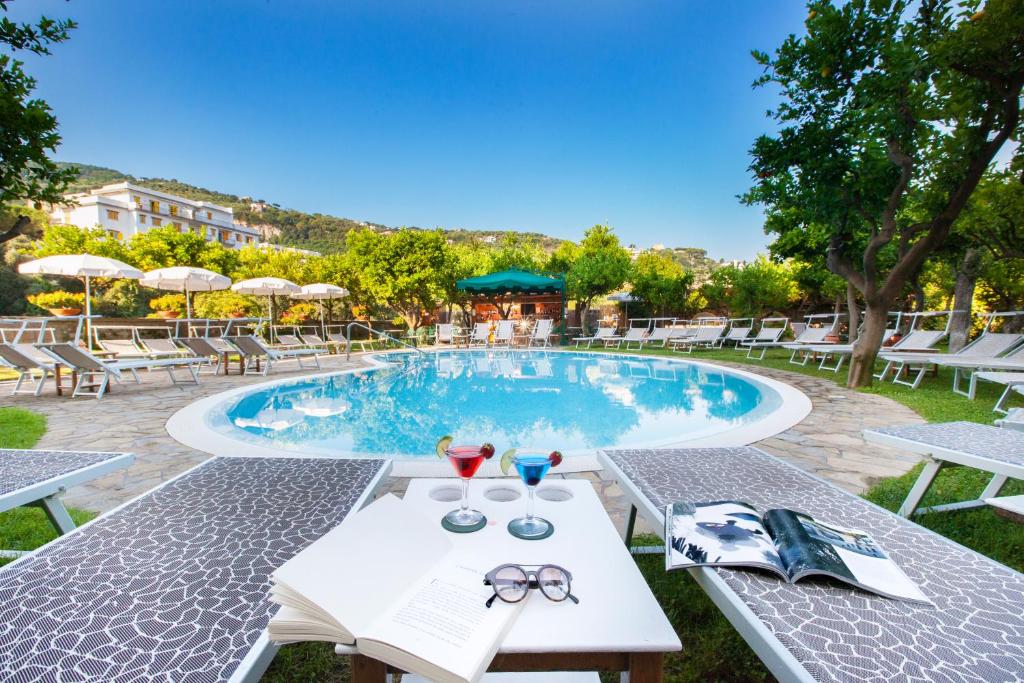 una piscina con sedie e un tavolo con bicchieri di Hotel Antiche Mura a Sorrento