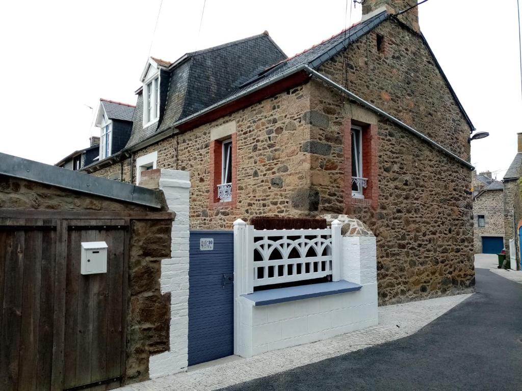 een huis met een witte poort en een bakstenen gebouw bij la petite maison du Portrieux in Saint-Quay-Portrieux