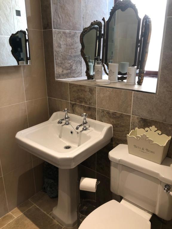 a bathroom with a sink and a toilet and mirrors at Belmont House Boutique - the Kingsley collection in Berwick-Upon-Tweed