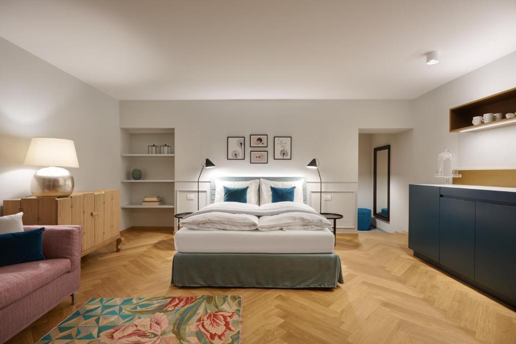 sypialnia z łóżkiem z niebieskimi poduszkami i kanapą w obiekcie Cityflair Boutique Apartments w mieście Bolzano