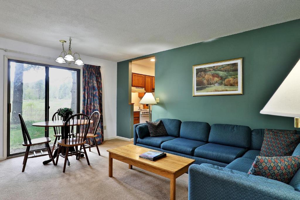 ein Wohnzimmer mit einem blauen Sofa und einem Tisch in der Unterkunft Cedarbrook Queen Suite 103 in Killington