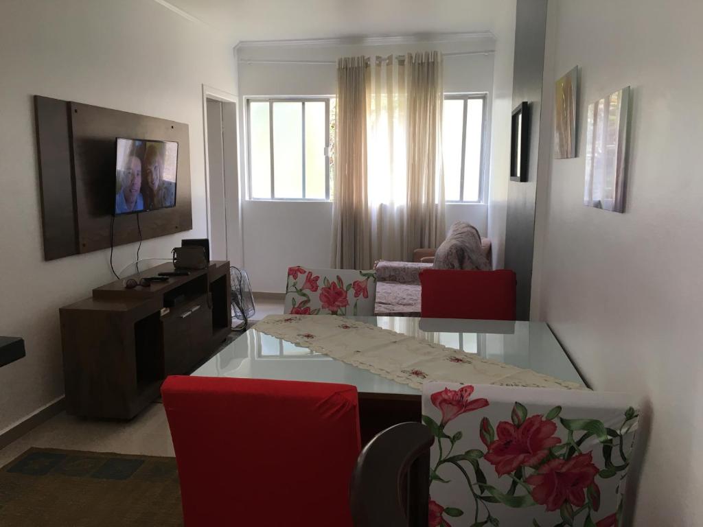 uma sala de estar com uma mesa de vidro e cadeiras vermelhas em Edifício Plaza de Saint Martin em Santos