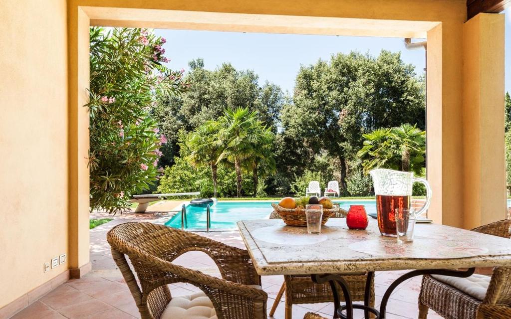 eine Terrasse mit einem Tisch, Stühlen und einem Pool in der Unterkunft Cottage Castelletto in Sinalunga