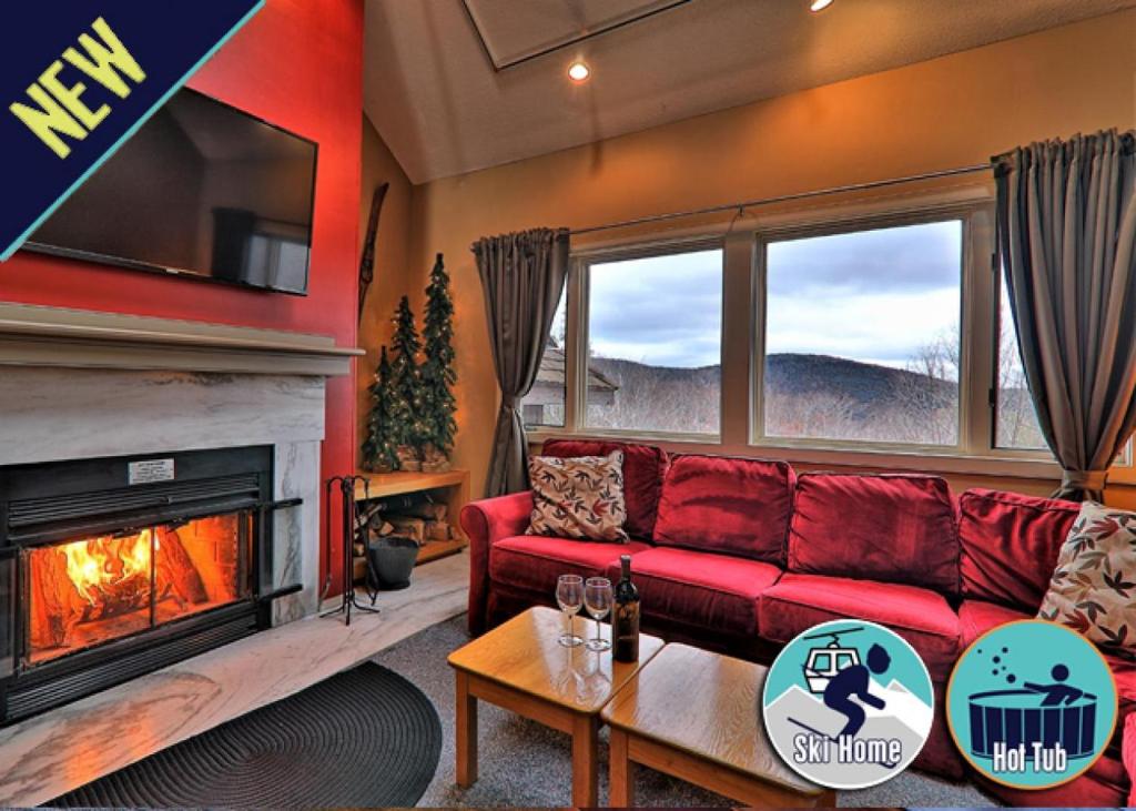 a living room with a red couch and a fireplace at Cozy,1 bedroom loft condo! Ski back trails, shuttle& Sports center Highridge E11 in Killington