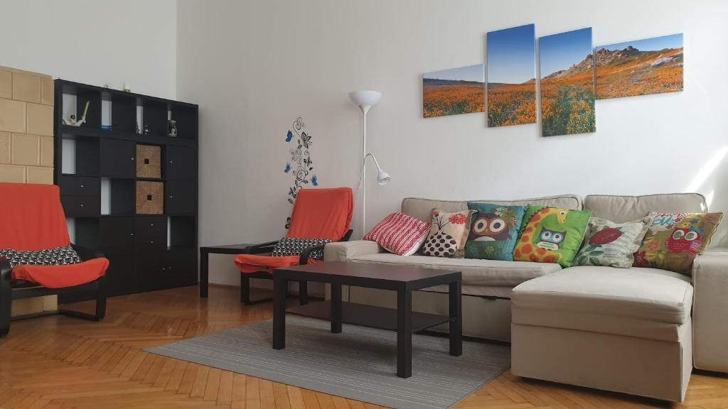 a living room with a couch and two orange chairs at Jolanda Apartment in Budapest