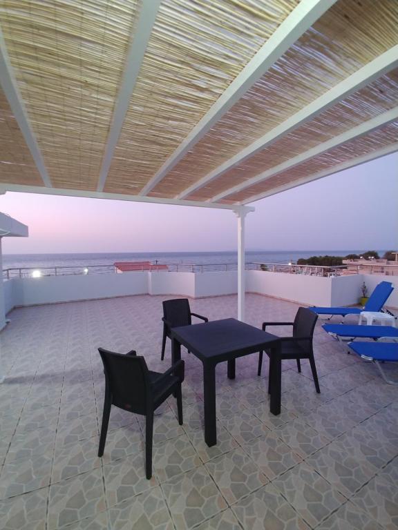 a patio with a table and chairs and the beach at Amazing Sea View Apartment in Amoudara Herakliou