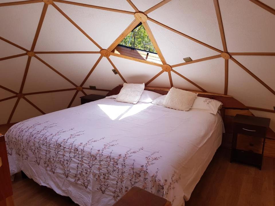 1 dormitorio con 1 cama blanca grande en una yurta en Jardín de domos: Pucon, en Pucón