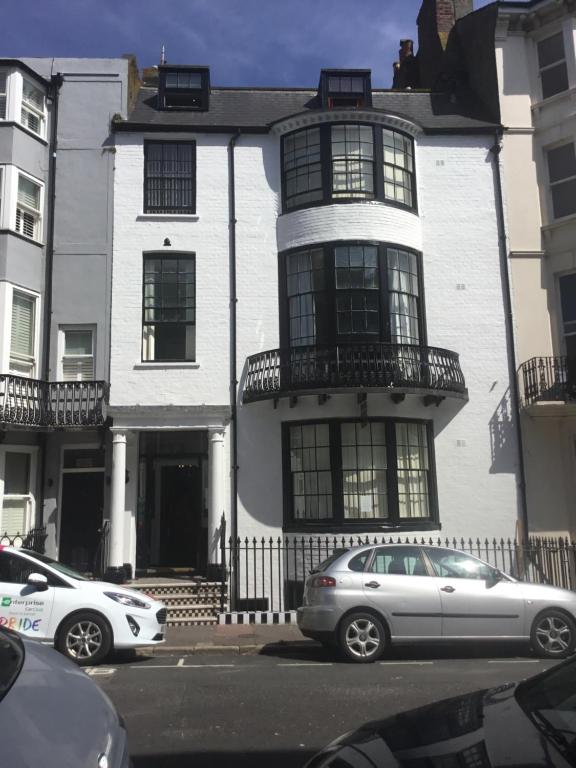 Una casa blanca con autos estacionados frente a ella. en Kempfield House, en Brighton & Hove