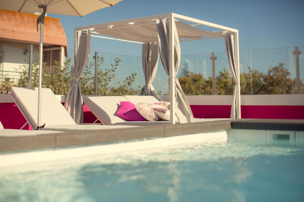 1 cama con dosel junto a la piscina en Chic Studios en Parede