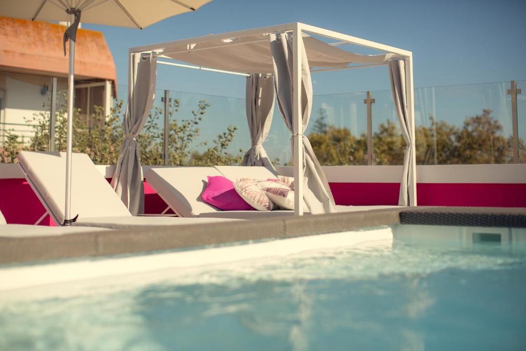 a bed with a canopy next to a swimming pool at Chic Studios in Parede