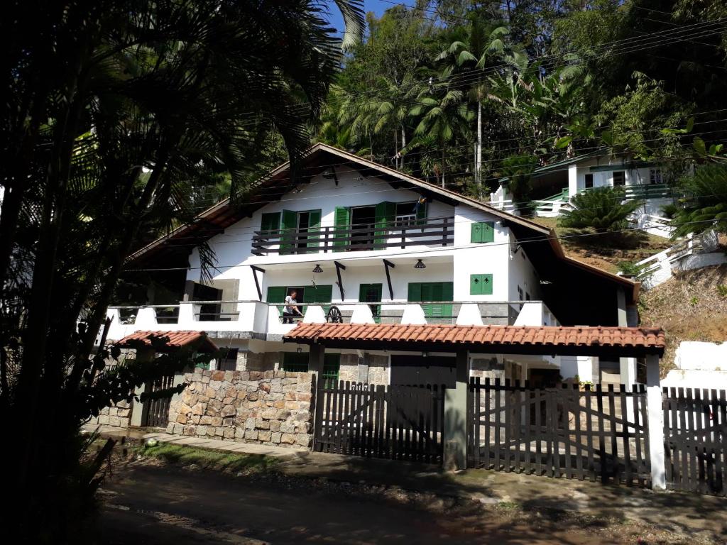 a white house with a fence in front of it at Encontro dos Mares Chalés Lázaro in Ubatuba