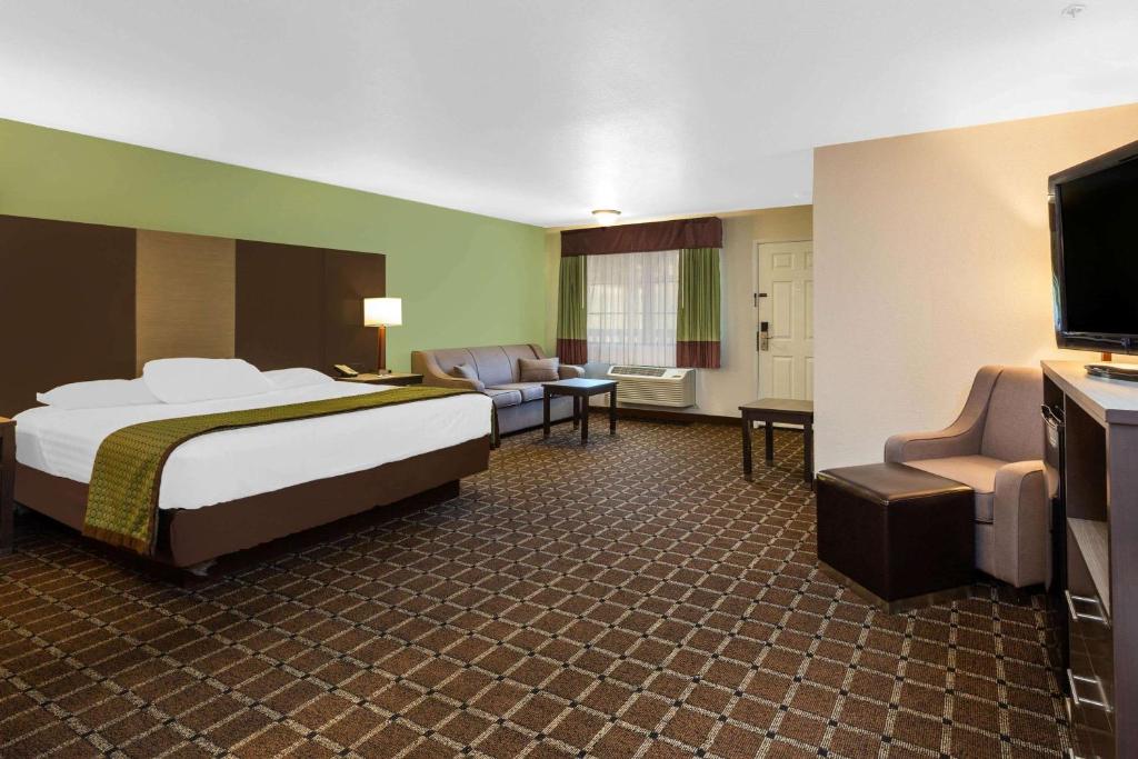 a hotel room with a bed and a couch and a television at Travelodge by Wyndham Angels Camp CA in Angels Camp