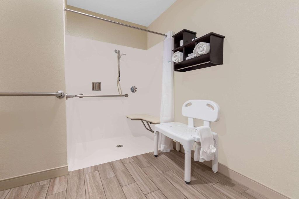 a bathroom with a white chair and a shower at Travelodge by Wyndham Angels Camp CA in Angels Camp