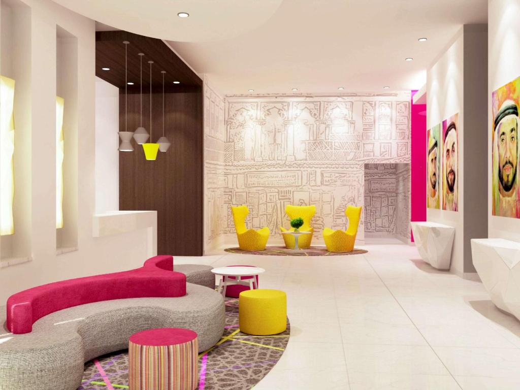 a living room with a pink couch and yellow chairs at ibis Styles Sharjah in Sharjah