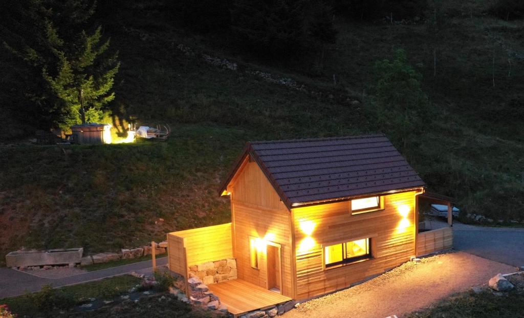uma pequena casa de madeira com luzes à noite em Le Cabanon de LaFermeDuNol em La Bresse