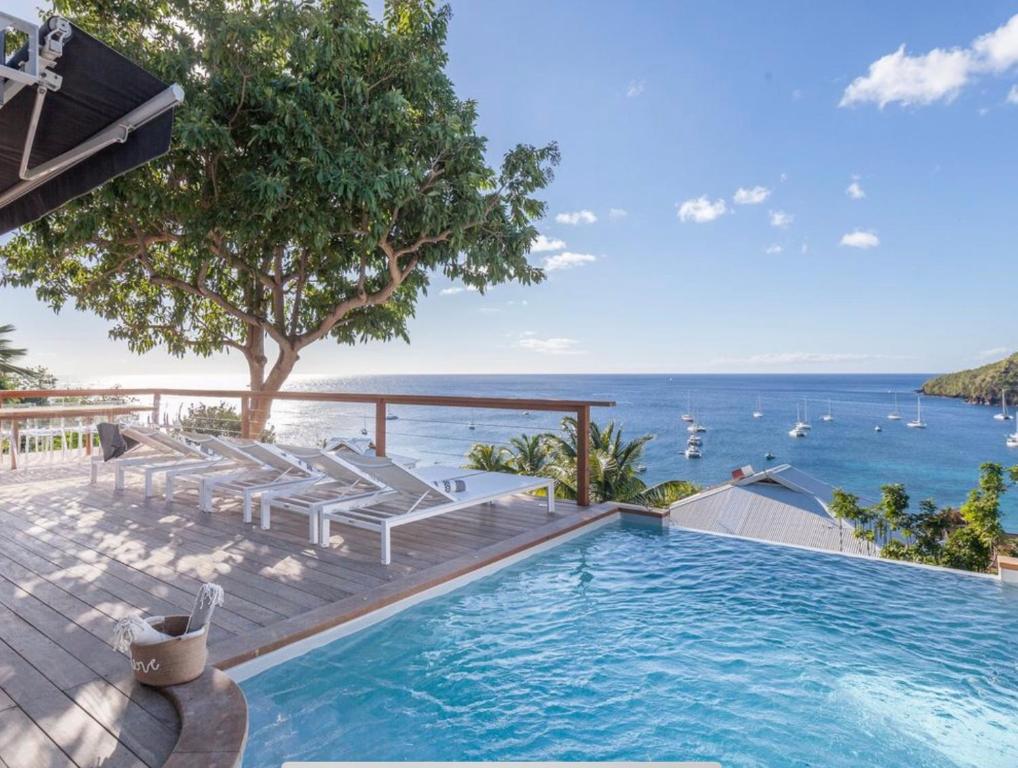 a swimming pool with chairs and a view of the ocean at Villa Ondines in Les Anses-dʼArlets