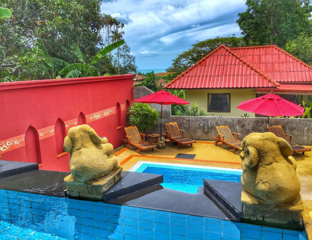 a pool with two statues of elephants next to a house at Chor Chang Villa Resort in Choeng Mon Beach