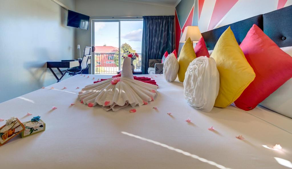 a bed with many different colored pillows on it at Silver Fern Lodge in Taupo