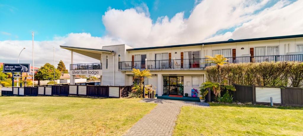 a white building with a lawn in front of it at Silver Fern Lodge in Taupo