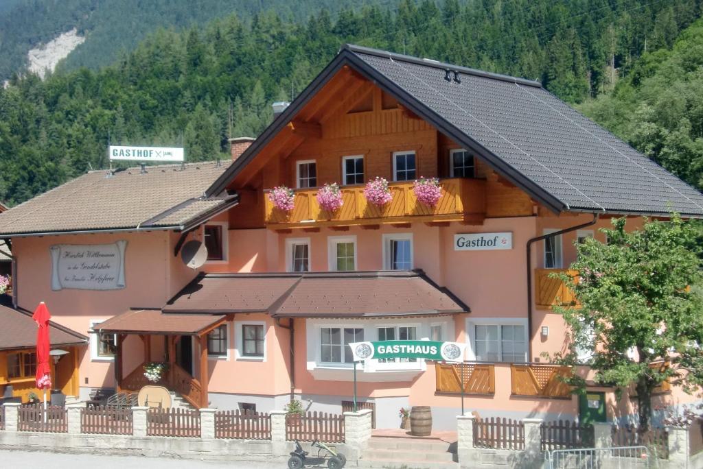 a large wooden building with flowers on the balcony at Pension Gondelstube in Schladming