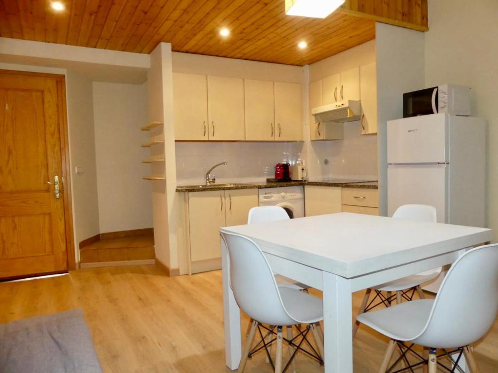 a kitchen with a white table and white chairs at DÚPLEX Acollidor al Centre de Vic APTGARBI in Vic