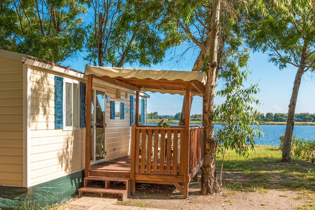 domek z werandą i drzewem w obiekcie Camping Village Laguna Blu w mieście Fertilia