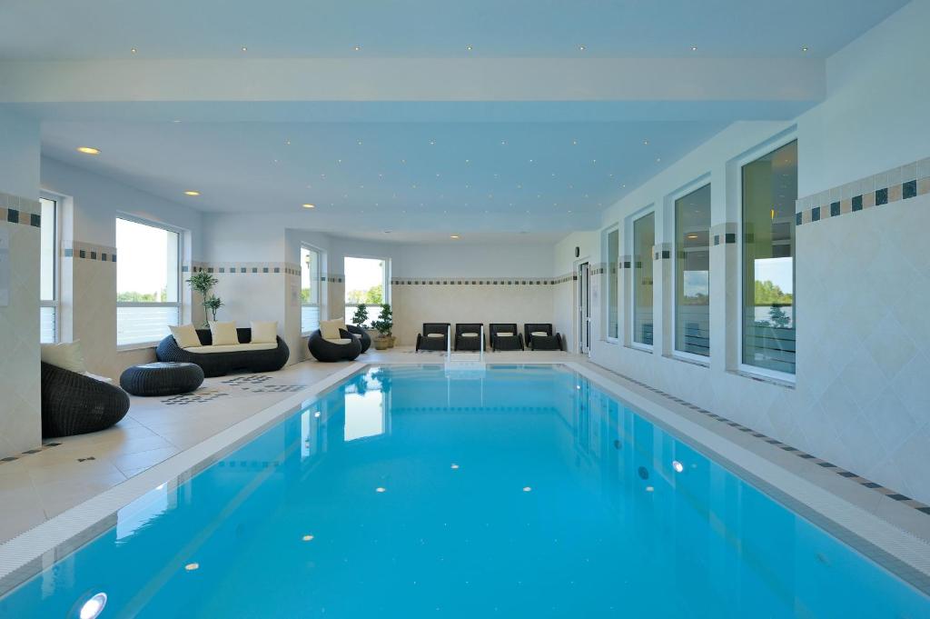 a large swimming pool with blue water in a house at Hotel Godewind in Thiessow