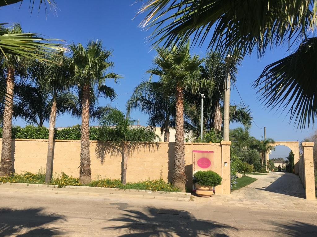 a street with palm trees and a pink wall at Villa Casole Short Lets in Copertino
