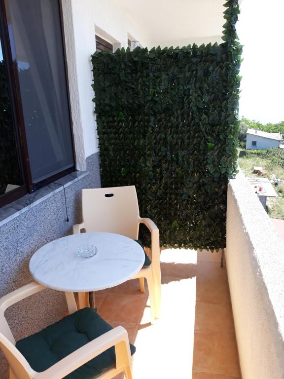 a table and chairs on a balcony with a green hedge at Apartments Petrovic in Krimovice