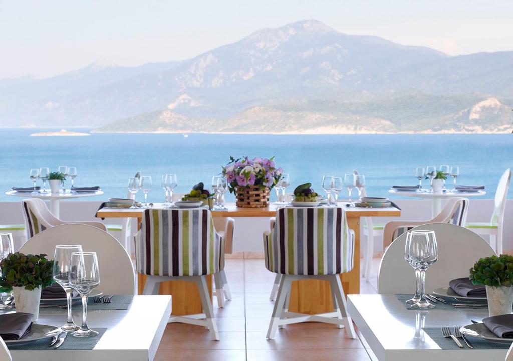 a table with chairs and a view of the ocean at Proteas Blu Resort in Pythagoreio