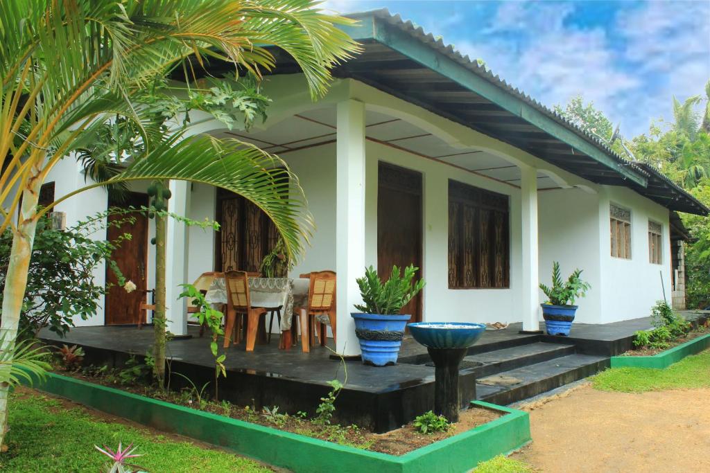 een klein wit huis met een tafel en stoelen bij Nature Night Homestay in Sigiriya
