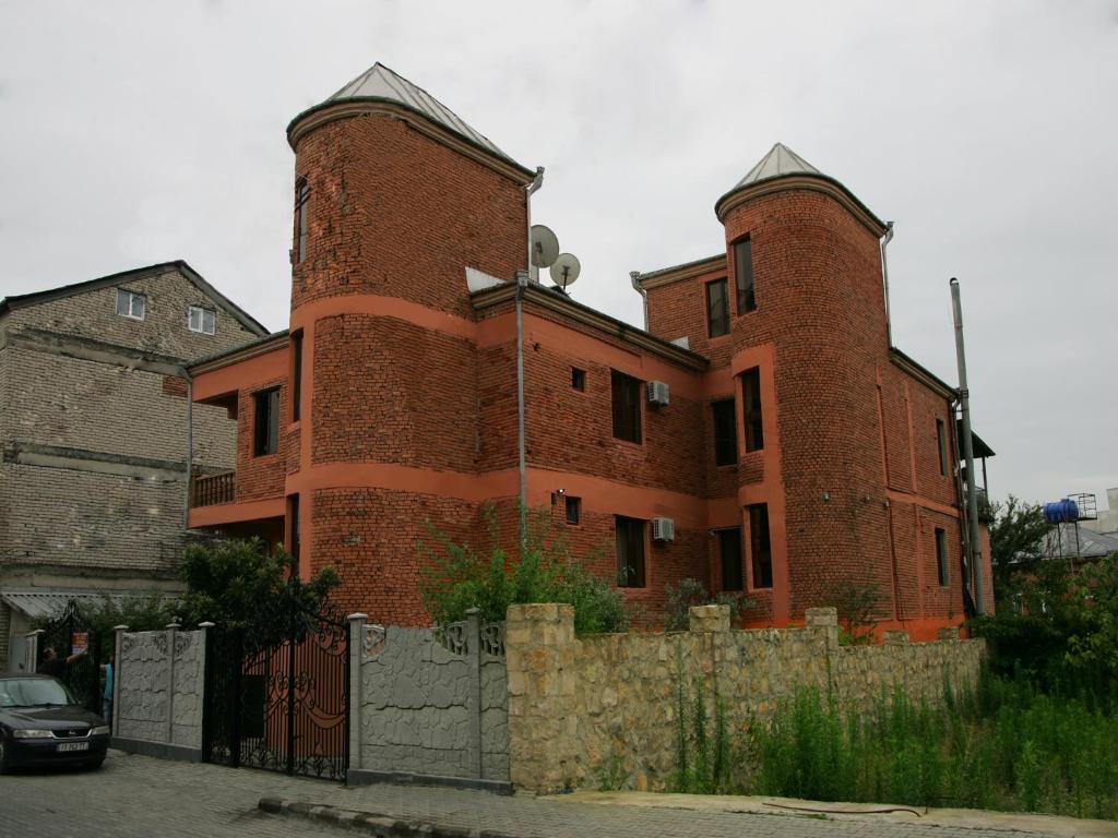 ein großes rotes Backsteingebäude mit zwei Türmen in der Unterkunft Two Towers Guest House in Kutaissi