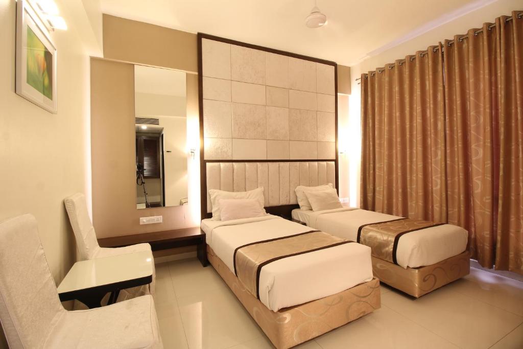 a hotel room with two beds and a chair at Hotel Executive Silver Inn in Aurangabad