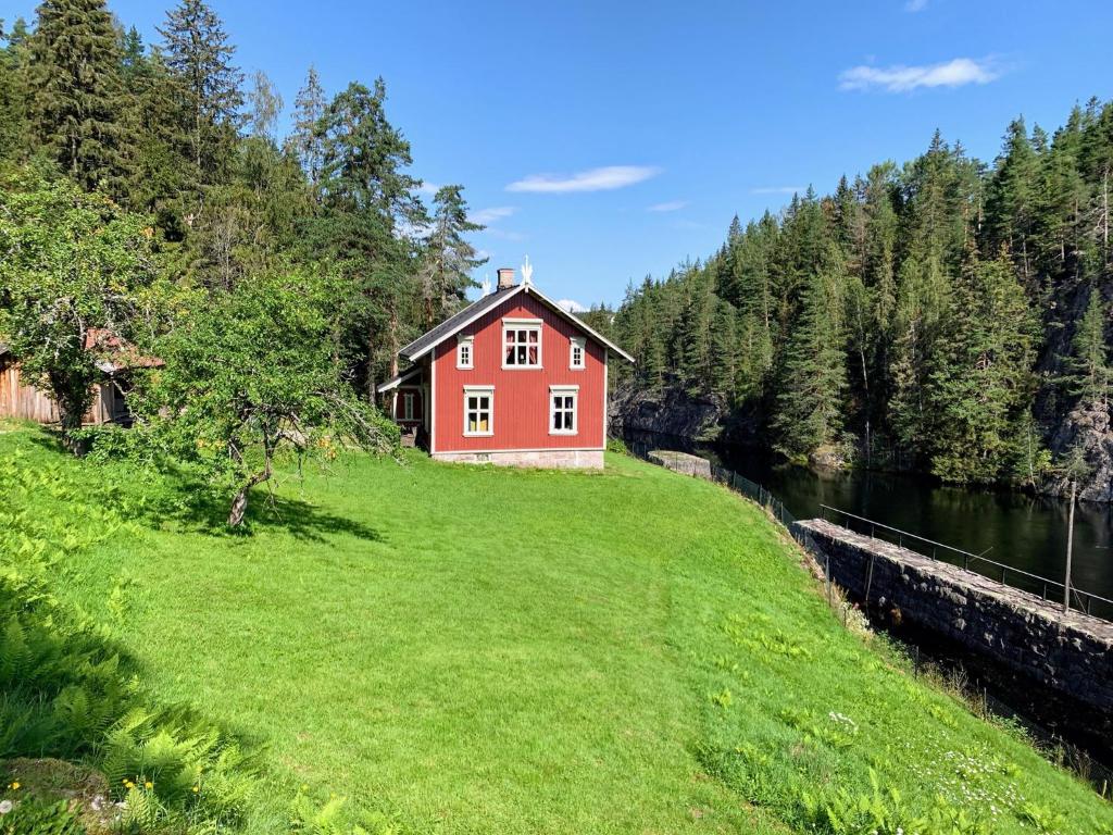 una casa rossa su una collina erbosa vicino a un fiume di vrangfoss slusevokterbolig a Funnemark