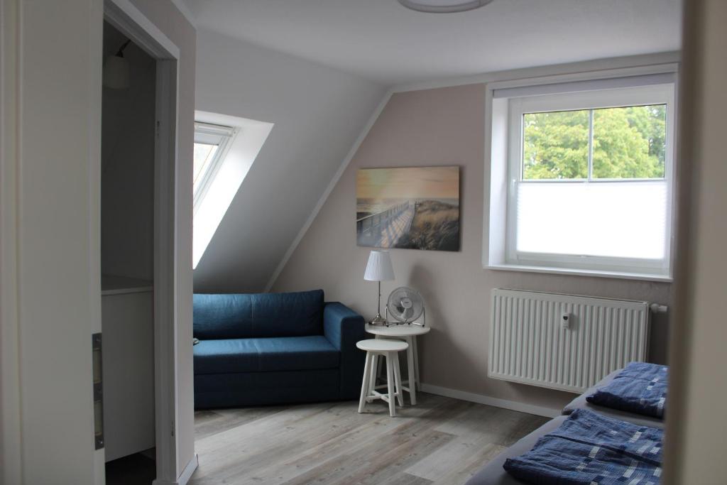 a living room with a blue couch and a window at Op'n Dörp Apartments in Barsbek