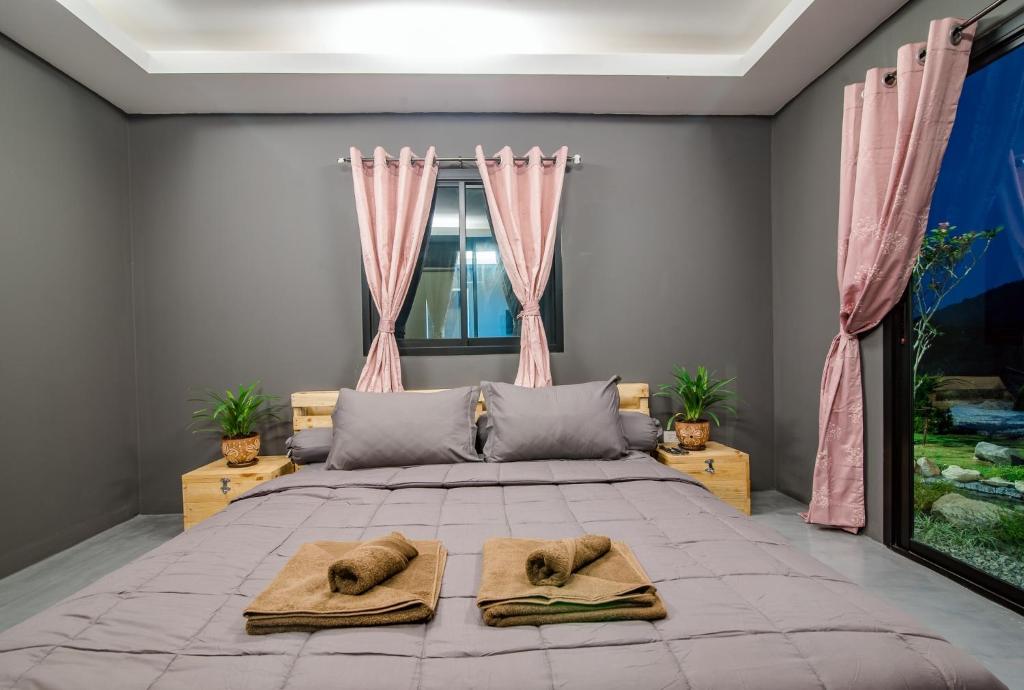a bedroom with a large bed with two towels on it at Hua Hin Lae I Aoon in Hua Hin
