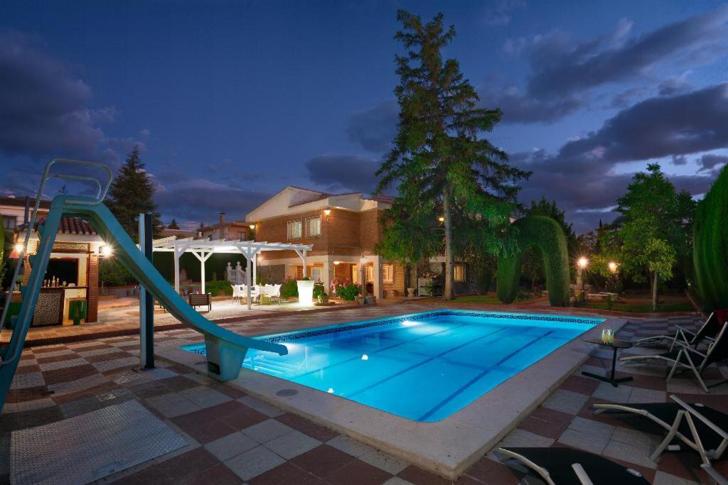 a swimming pool with a slide in front of a house at NEW. LUXURY VILLA C&C. JARDÍN, PISCINA Y BARBACOA in Granada