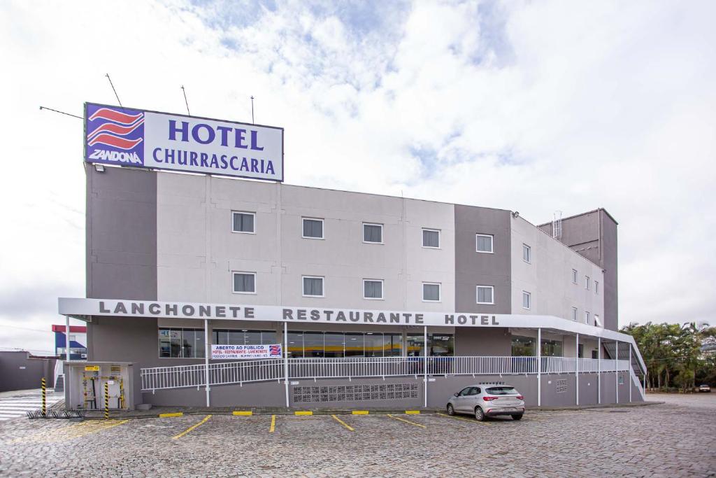 a hotel with a car parked in a parking lot at Hotel Zandoná in Blumenau