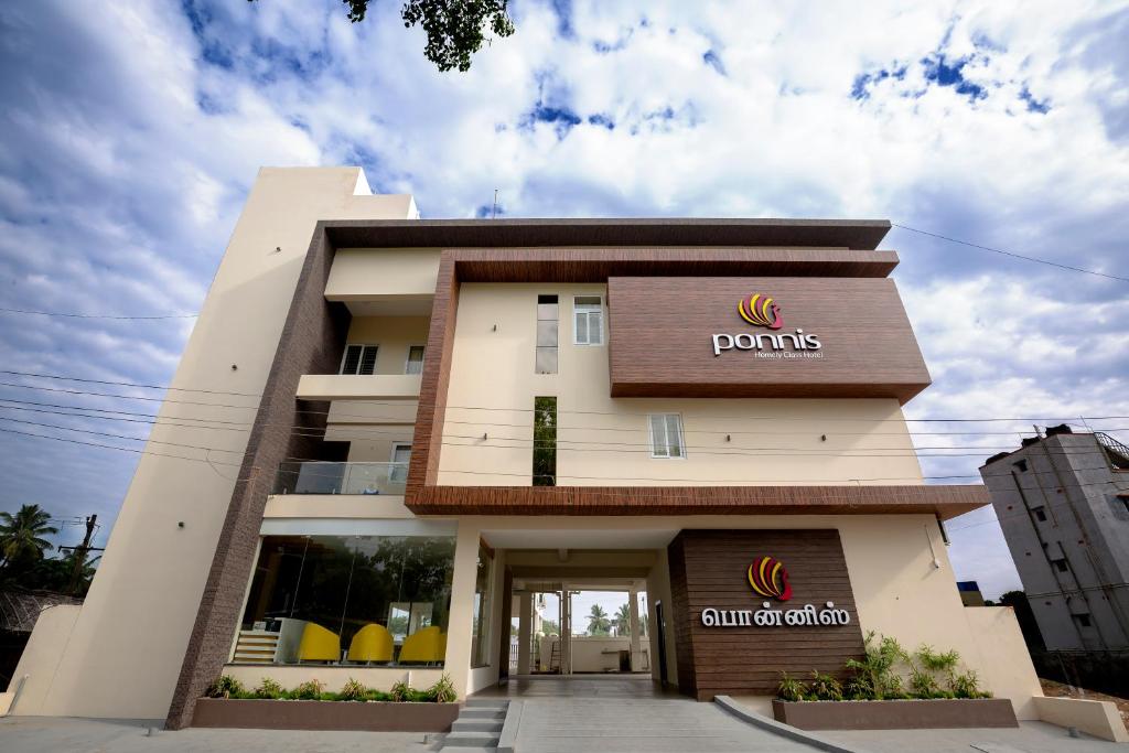 帕拉尼Ponnis Hotel的建筑正面景色,上面有标志